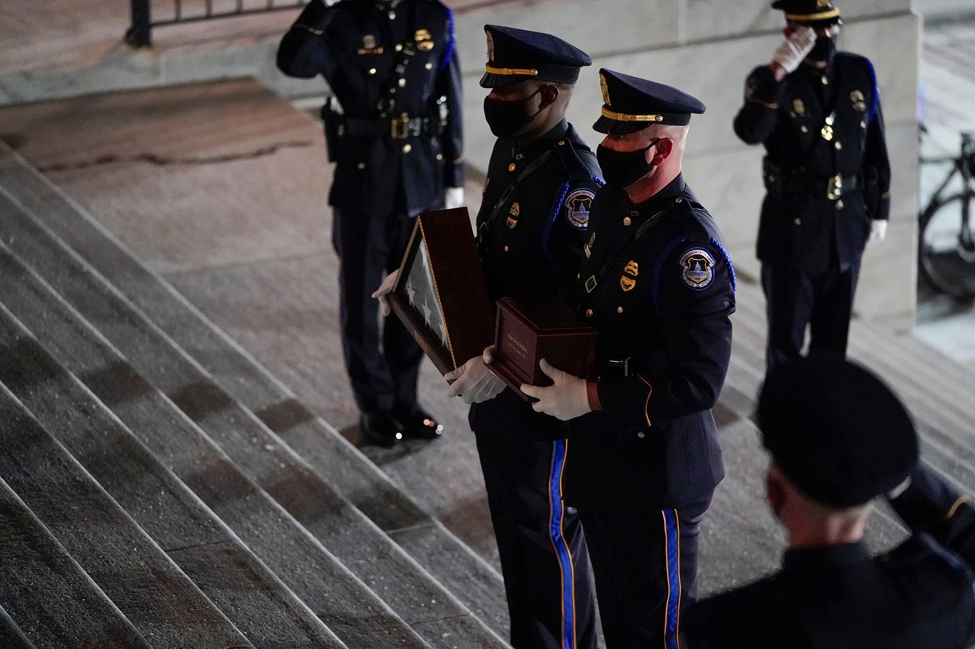 An honor guard carries an urn with the cremated remains of U.S. Capitol Police officer Brian Sicknick and folded flag up the steps of the U.S Capitol to lie in honor in the Rotunda, Tuesday, Feb. 2, 2021, in Washington.