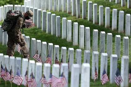 Wearing face masks to reduce the risk of spreading the novel coronavirus, soldiers from the 3rd Infantry Regiment, also called the "Old Guard," place U.S. flags in front of every grave site ahead of the Memorial Day weekend in Arlington National Cemetery on May 21, 2020, in Arlington, Va.