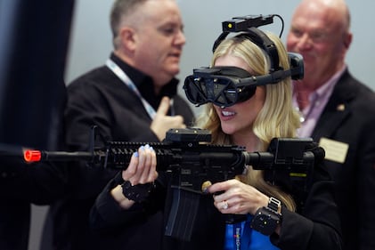 A woman engages with a shooting simulation at the General Dynamics Information Technology booth at the West 2024 conference in San Diego.