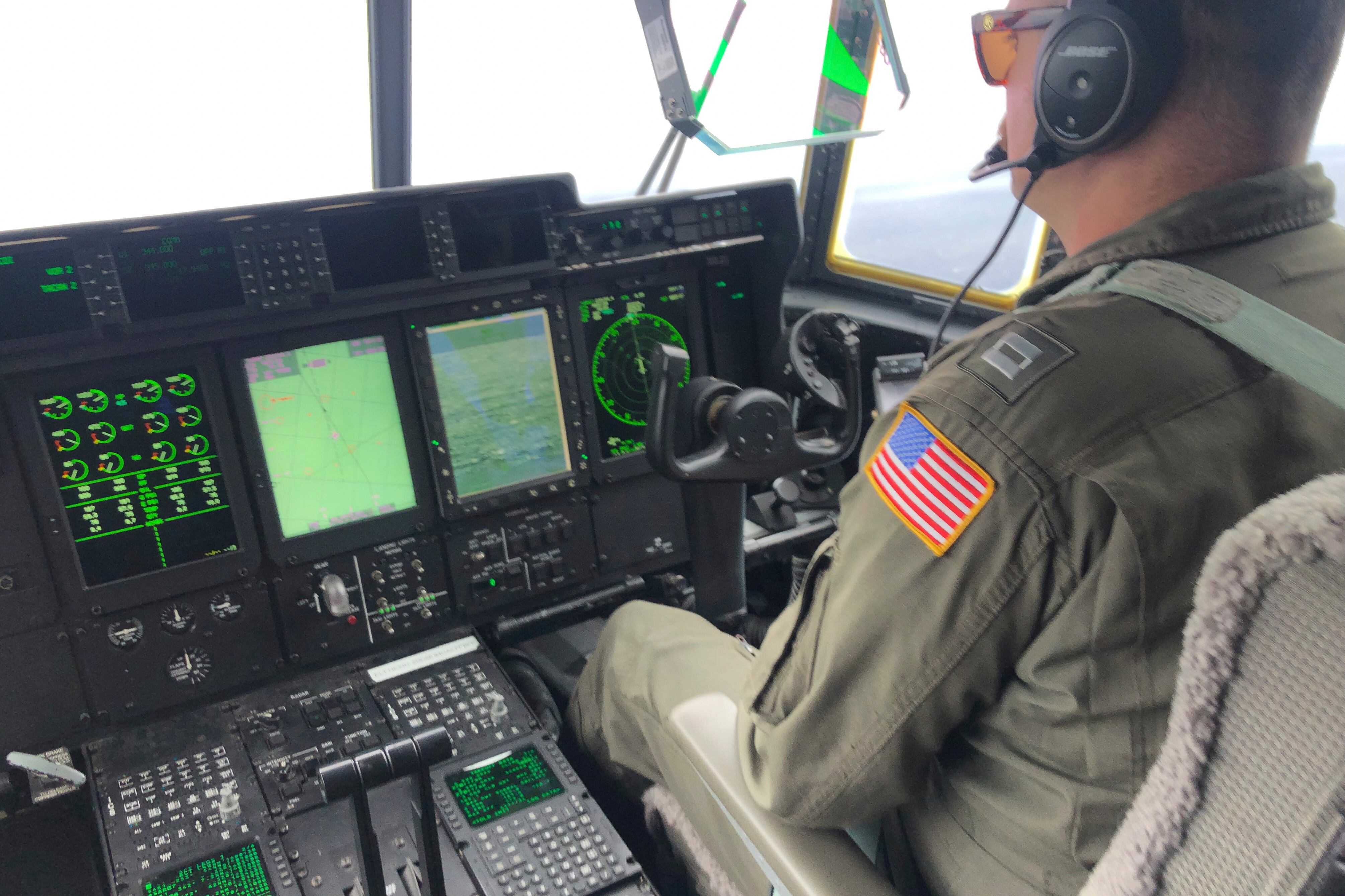 In this image provided by the U.S. Coast Guard, a crew member sits aboard a Coast Guard HC-130 Hercules airplane based at Coast Guard Air Station Elizabeth City, N.C., as it flies about 900 miles East of Cape Cod, Mass., during the search for the 21-foot submersible, Titan, Wednesday, June 21, 2023.