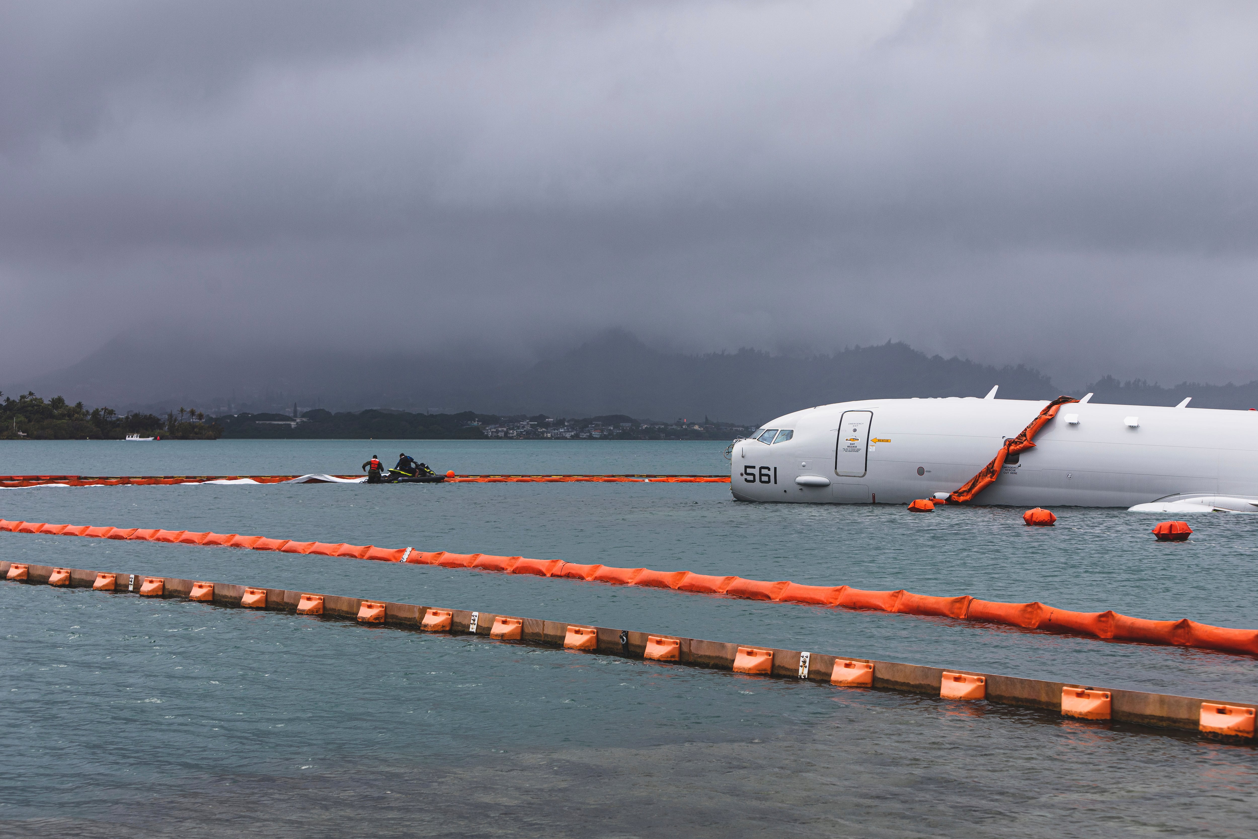 This Nov. 21, 2023, handout photo provided by the U.S. Marine Corps shows U.S. Navy sailors deploying temporary protective barriers around a downed Navy P-8A in waters just off the runway at Marine Corps Air Station Kaneohe Bay in Kaneohe Bay, Hawaii.