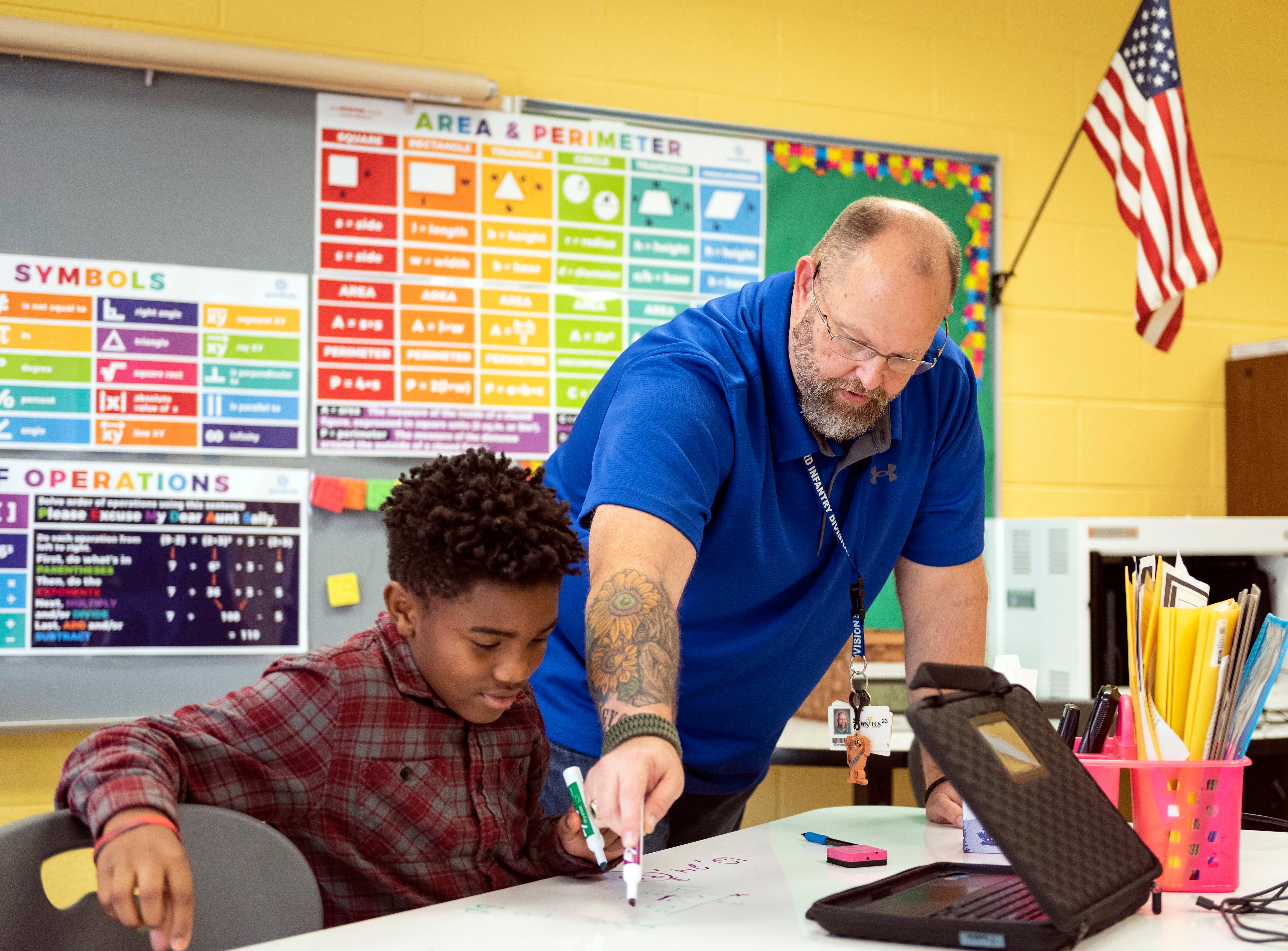 Retired Army veteran Christopher Simmons and E.C. teacher guides seventh-grader Elijah Williams through a math problem on Wednesday, Nov. 9, 2022, at Meadowlark Middle School in Winston-Salem, N.C.