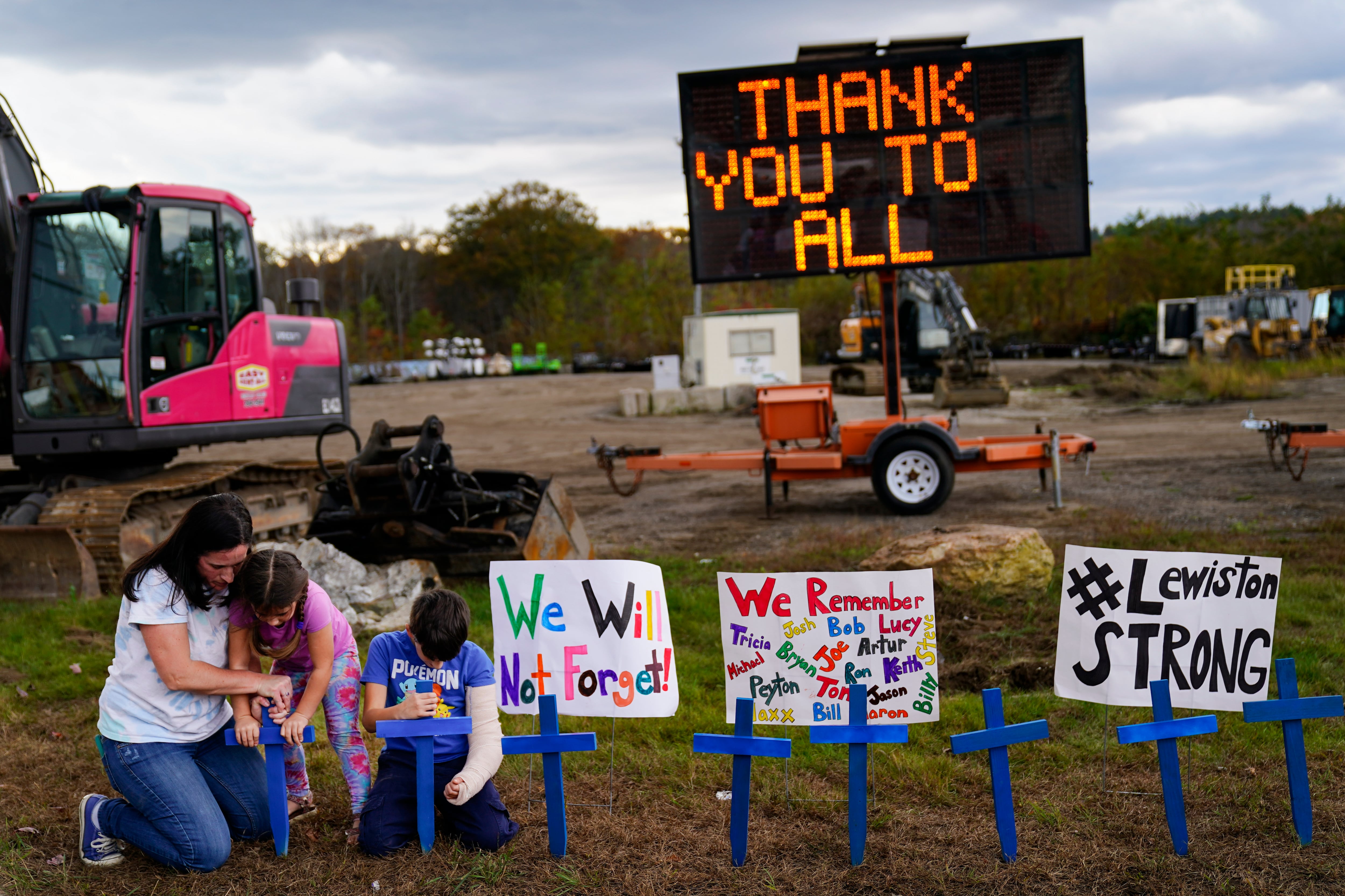 Bre Allard, accompanied by her children Lucy, 5, and Zeke, 8, plant crosses in honor of the victims of this week's mass shooting in Lewiston, Maine, Saturday, Oct. 28, 2023.