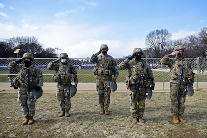 Members of the National Guard salute as they stand near the Capitol while the national anthem is sung during the inauguration of President-elect Joe Biden and Vice President-elect Kamala Harris on Jan. 20, 2021, in Washington.