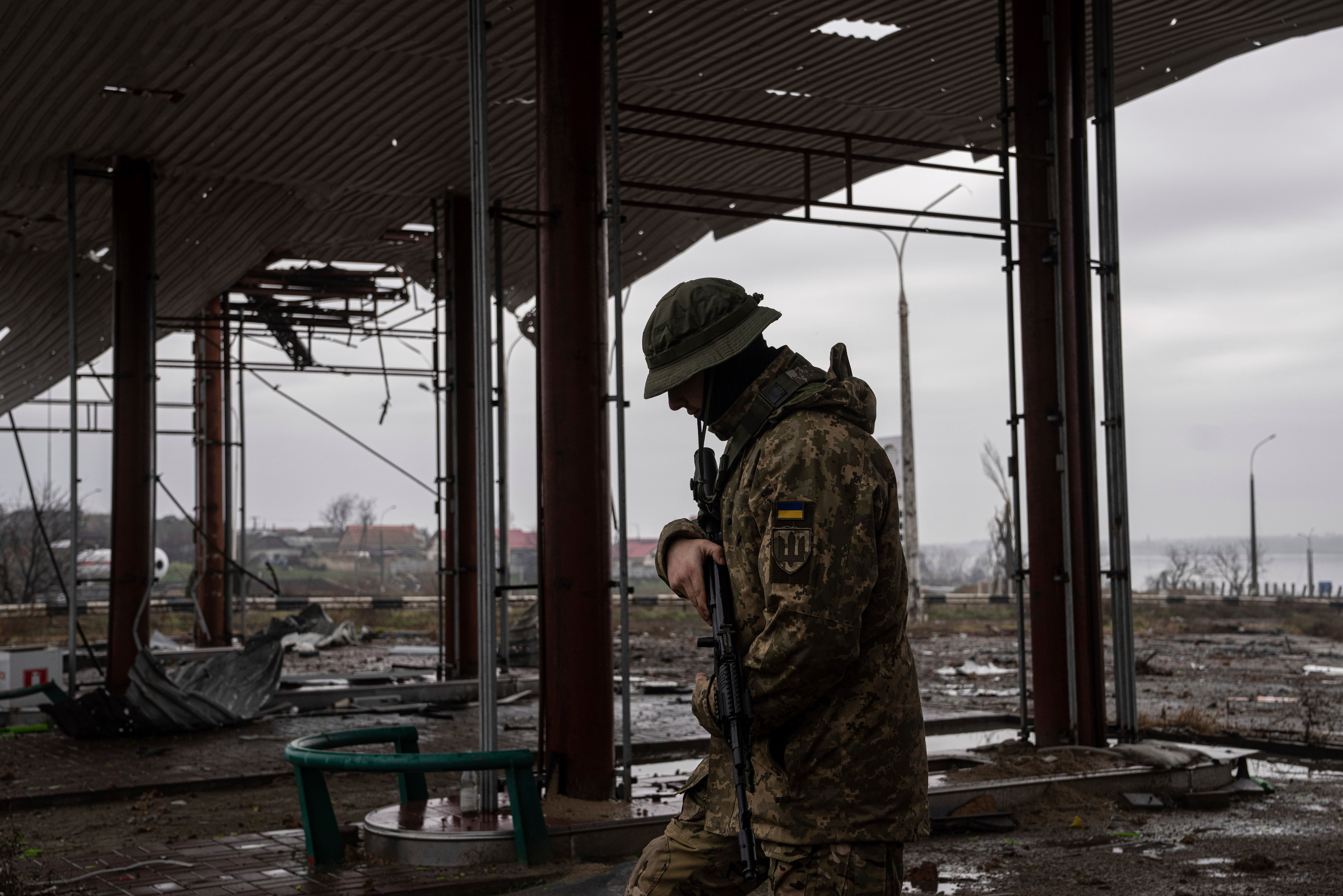 A Ukrainian serviceman patrols area near the Antonovsky Bridge which was destroyed by Russian forces after withdrawing from Kherson, Ukraine, Thursday, Dec. 8, 2022.