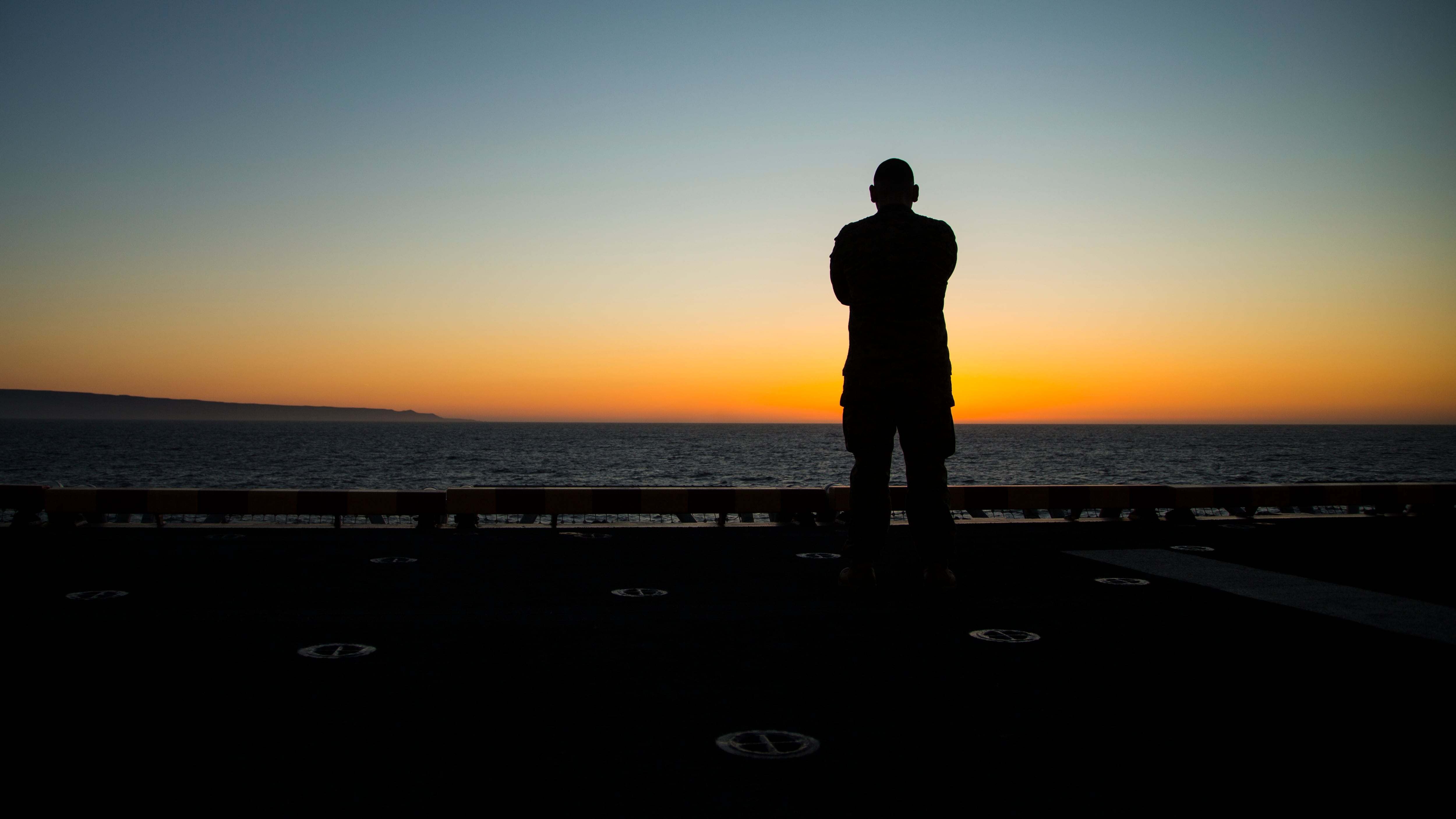 A Marine catches the sunrise before flight operations aboard the Wasp-class amphibious ship USS Essex, March 27, 2018.