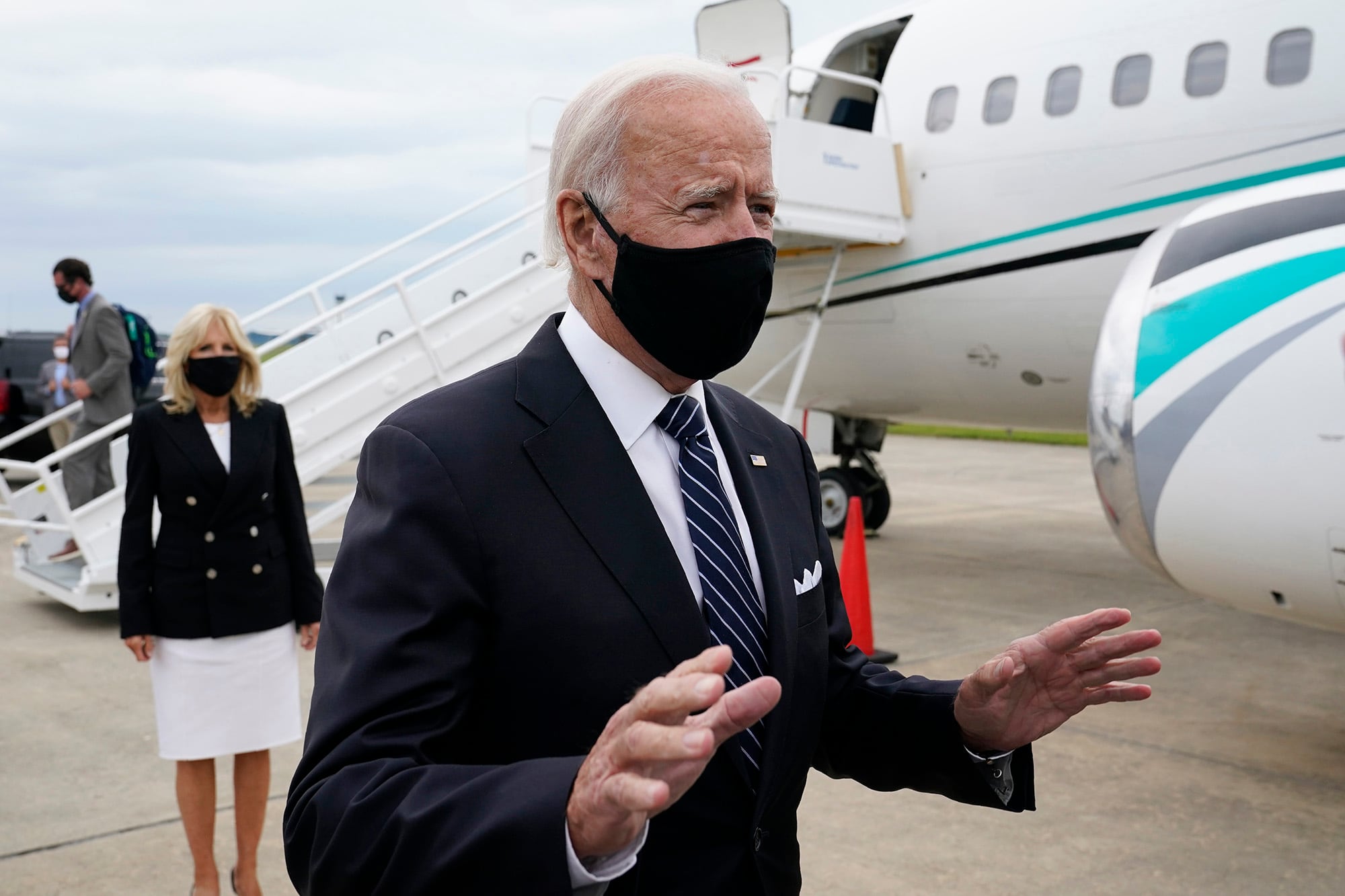 Democratic presidential candidate and former Vice President Joe Biden speaks with reporters after he and his wife Jill Biden, back left, stepped off a plane at New Castle Airport in New Castle, Del., Friday, Sept. 11, 2020.