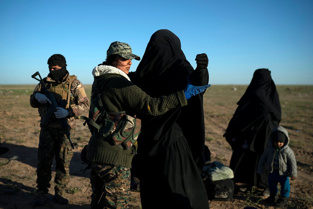 a woman is frisked by a U.S.-backed Syrian Democratic Forces fighter at a screening area after being evacuated out of the last territory held by Islamic State group militants.