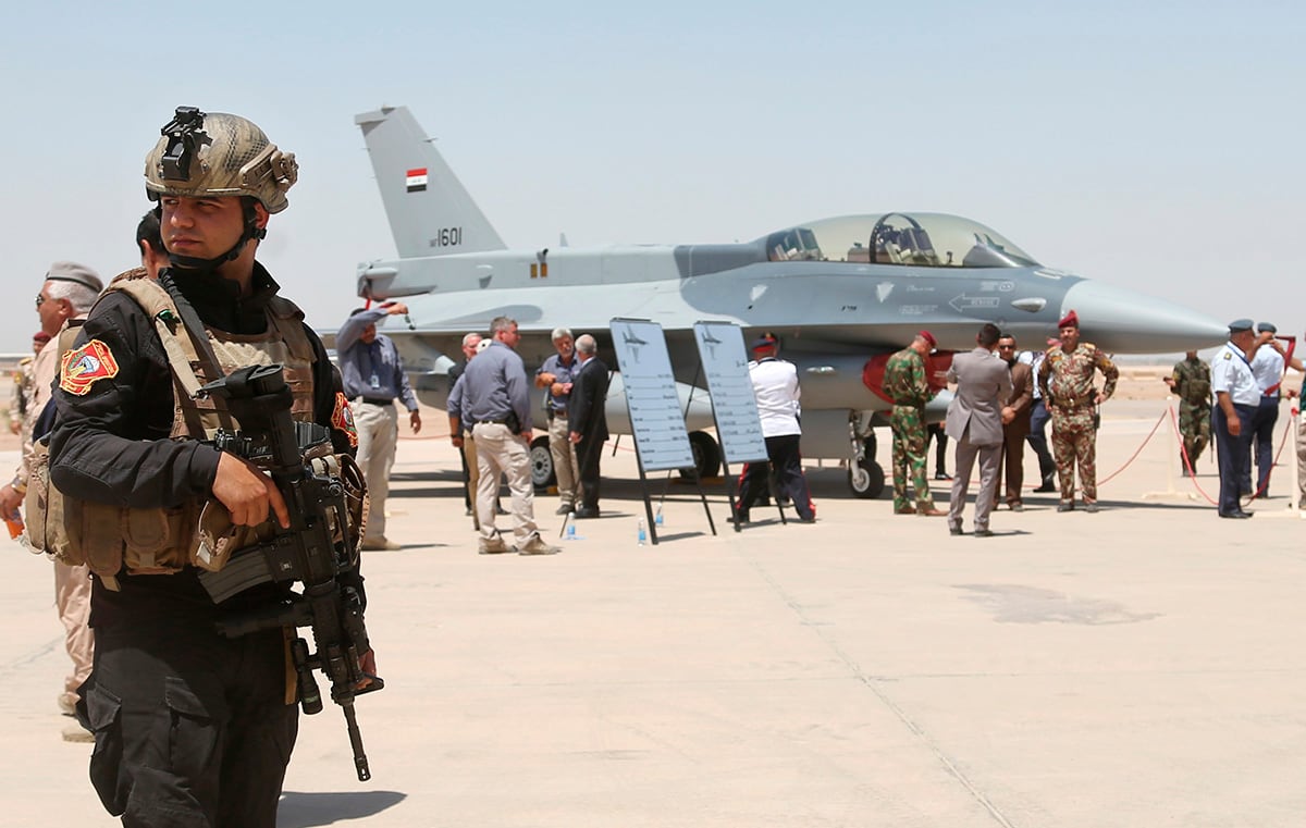 A member of the Iraqi SWAT team stands guard as security forces and others gather next to a U.S.- made F-16 fighter jet on July 20, 2015, during the delivery ceremony at Balad air base, Iraq.