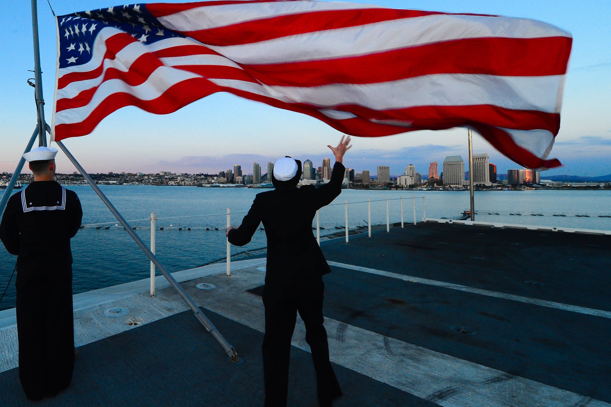 Aviation Ordnanceman 3rd Class Mason Adams, left, and Aviation Ordnanceman 3rd Class Tabitha Prine lower the national ensign during evening colors aboard the aircraft carrier USS Ronald Reagan (CVN 76) on March 10, 2014, at Naval Base Coronado.