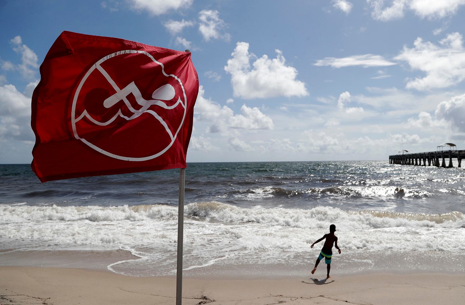 A boy plays on the beach as a No Swimming flag flies, Saturday, Aug. 31, 2019, in Lake Worth, Fla.