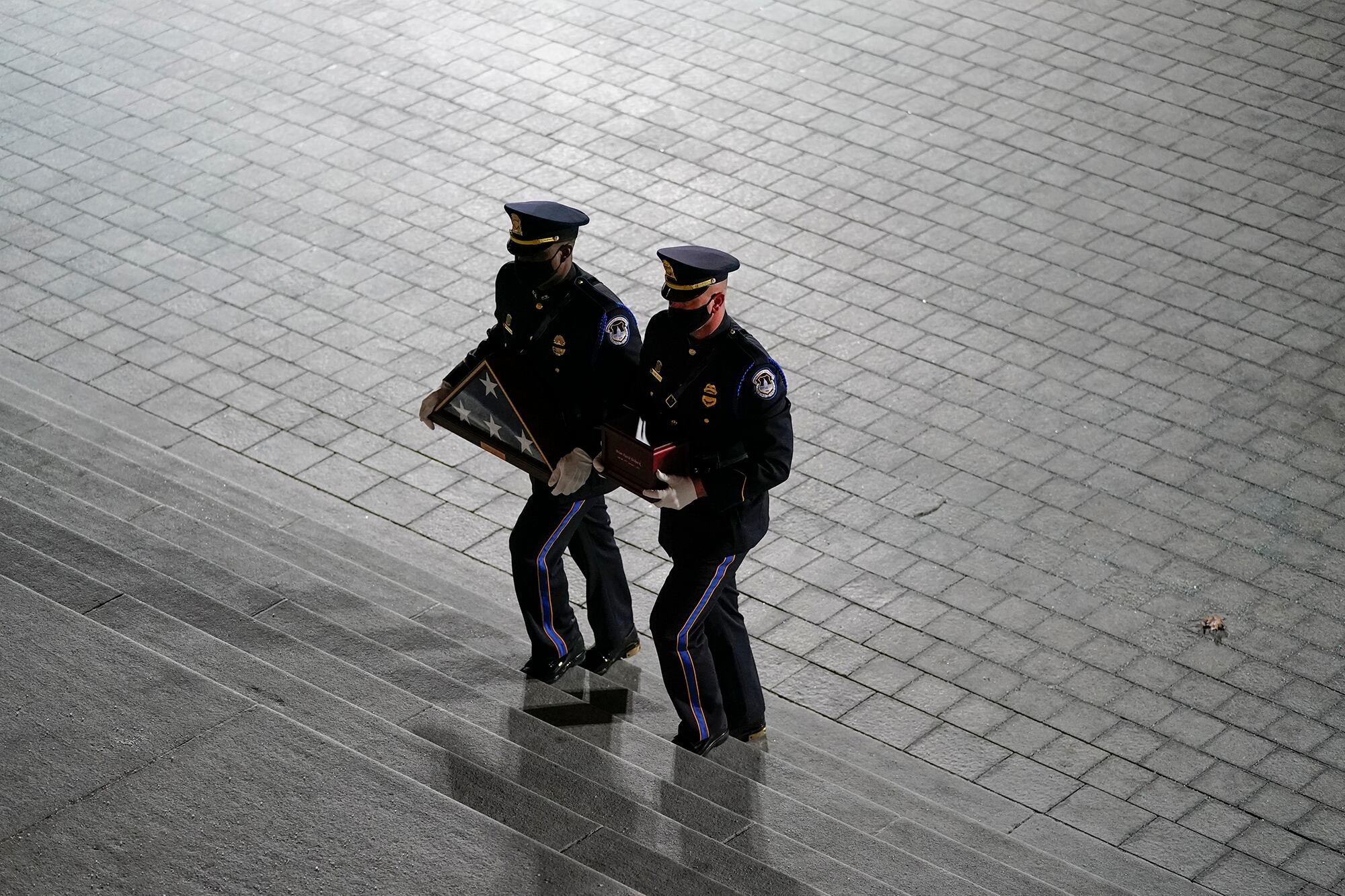 An honor guard carries an urn with the cremated remains of U.S. Capitol Police officer Brian Sicknick and folded flag up the steps of the U.S Capitol to lie in honor in the Rotunda, Tuesday, Feb. 2, 2021, in Washington.