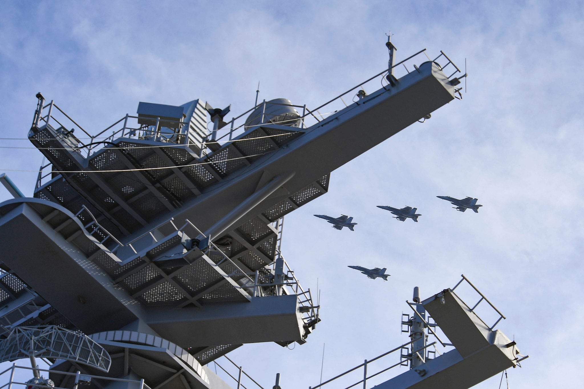 F/A-18 Super Hornets fly in formation over the aircraft carrier USS Theodore Roosevelt (CVN 71) on June 9, 2020, in the Philippine Sea.