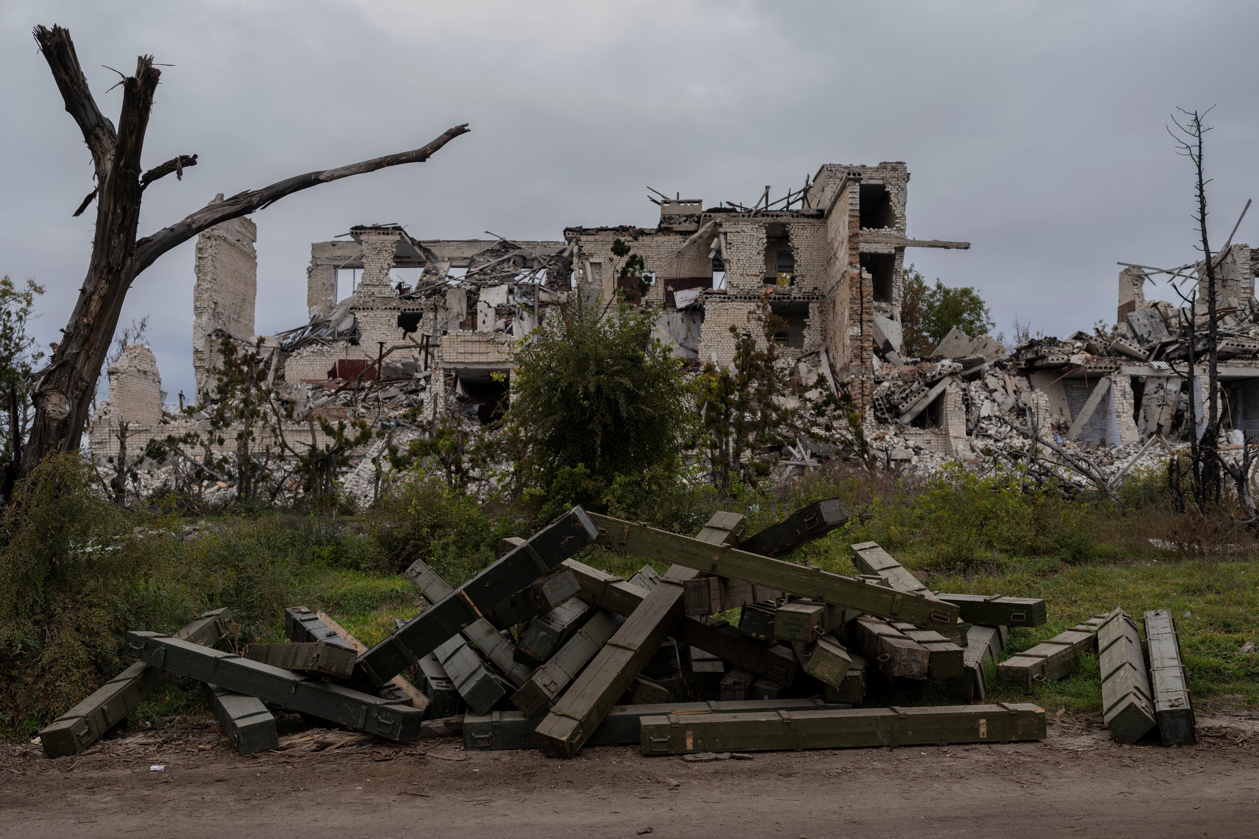 Ammunition boxes lay outside a destroyed school on the outskirts of a recently liberated village outskirts of Kherson, in southern Ukraine, Wednesday, Nov. 16, 2022.